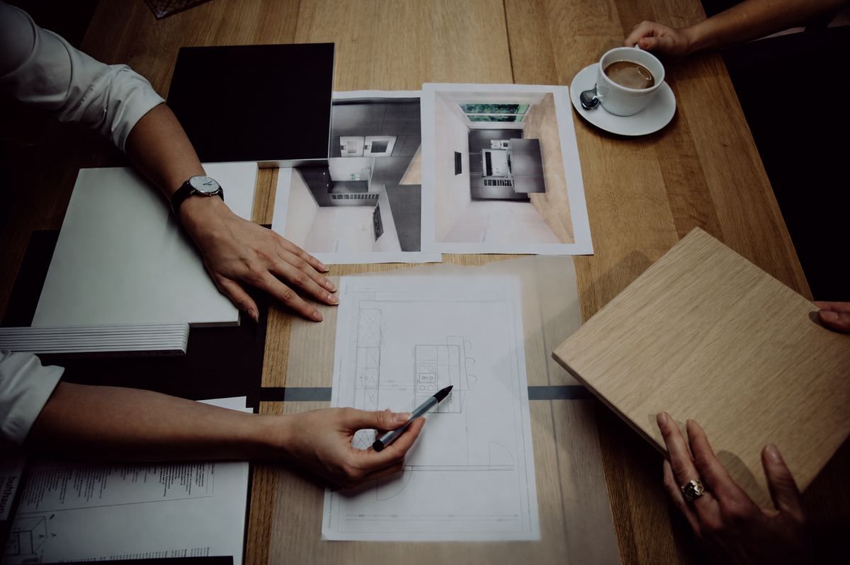 Beratungsgespräch mit Küchenplänen, Materialmustern und Kaffee auf dem Tisch