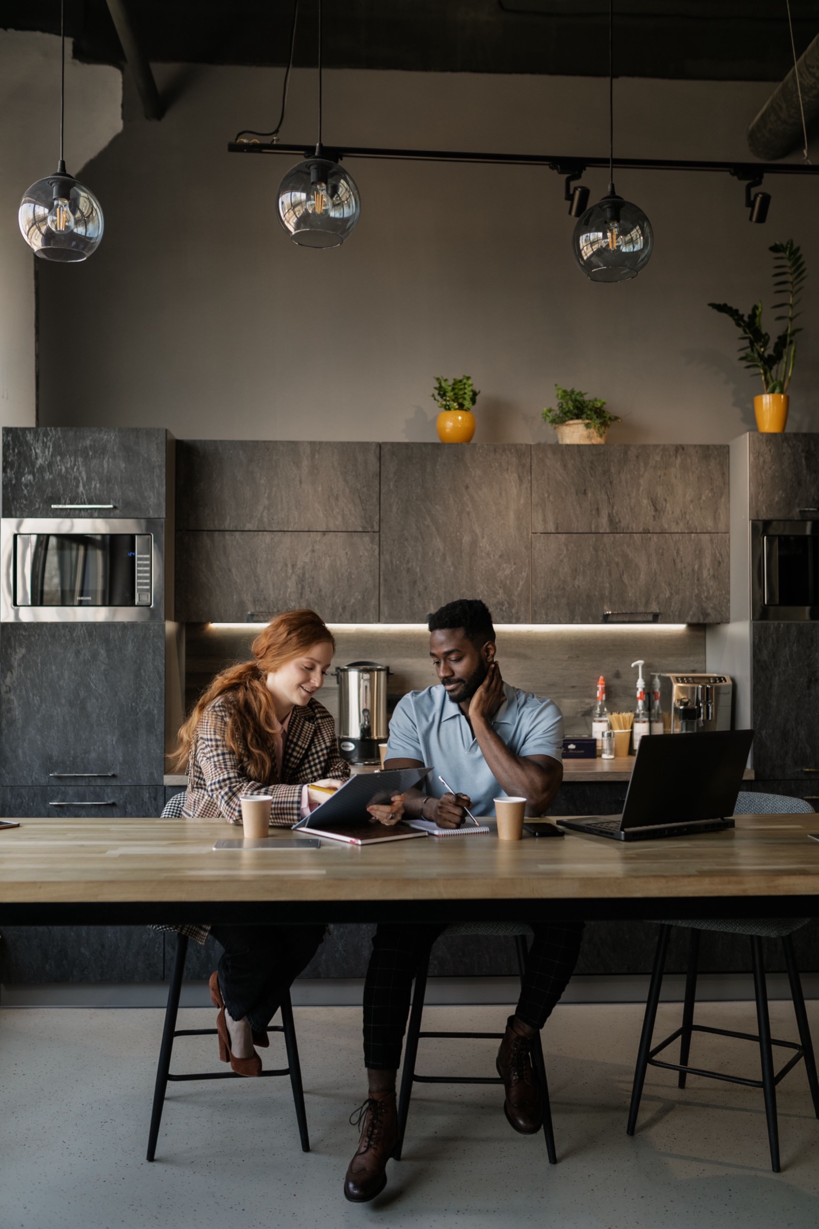 Zwei Kolleg:innen bei Kaffee und Gespräch an der Büroküche
