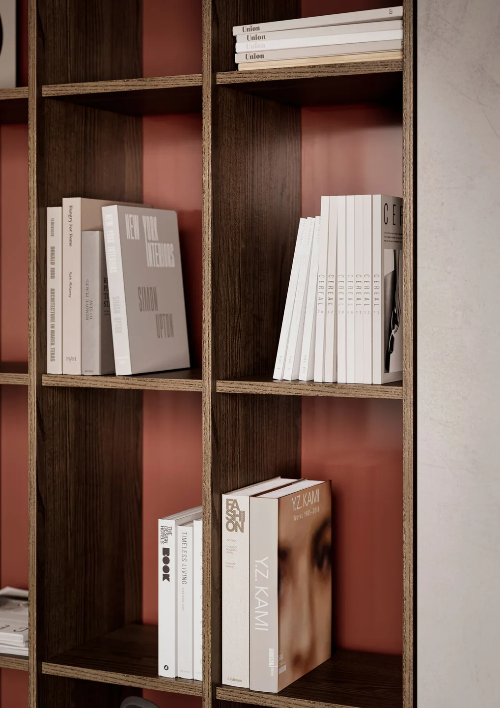 Detail eines Bücherregals in dunklem Holz mit terrakottafarbener Rückwand und Bildbänden